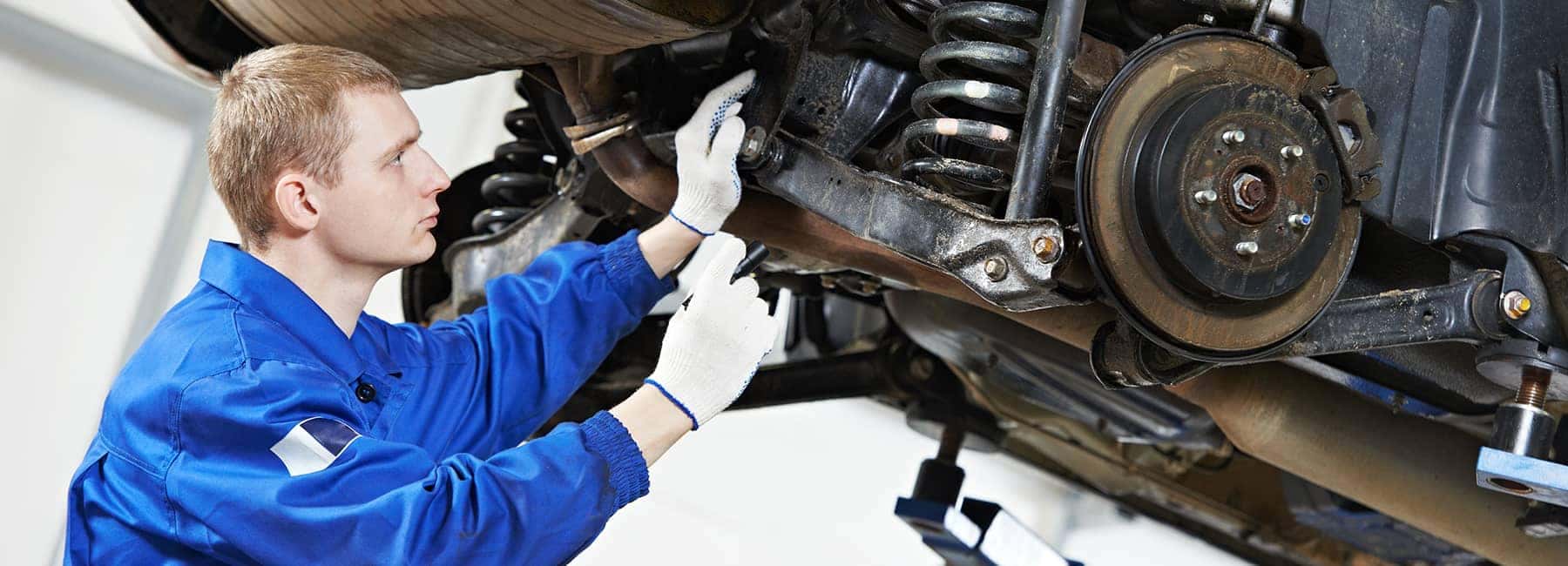 gloved technician examines underside of car
