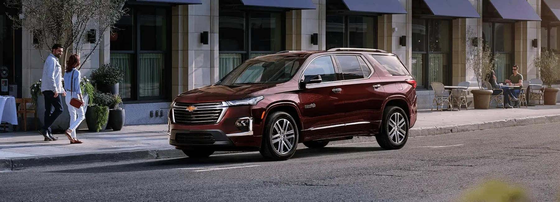 2023-Chevy-Traverse-parked-while-couple-walks-past-city-street