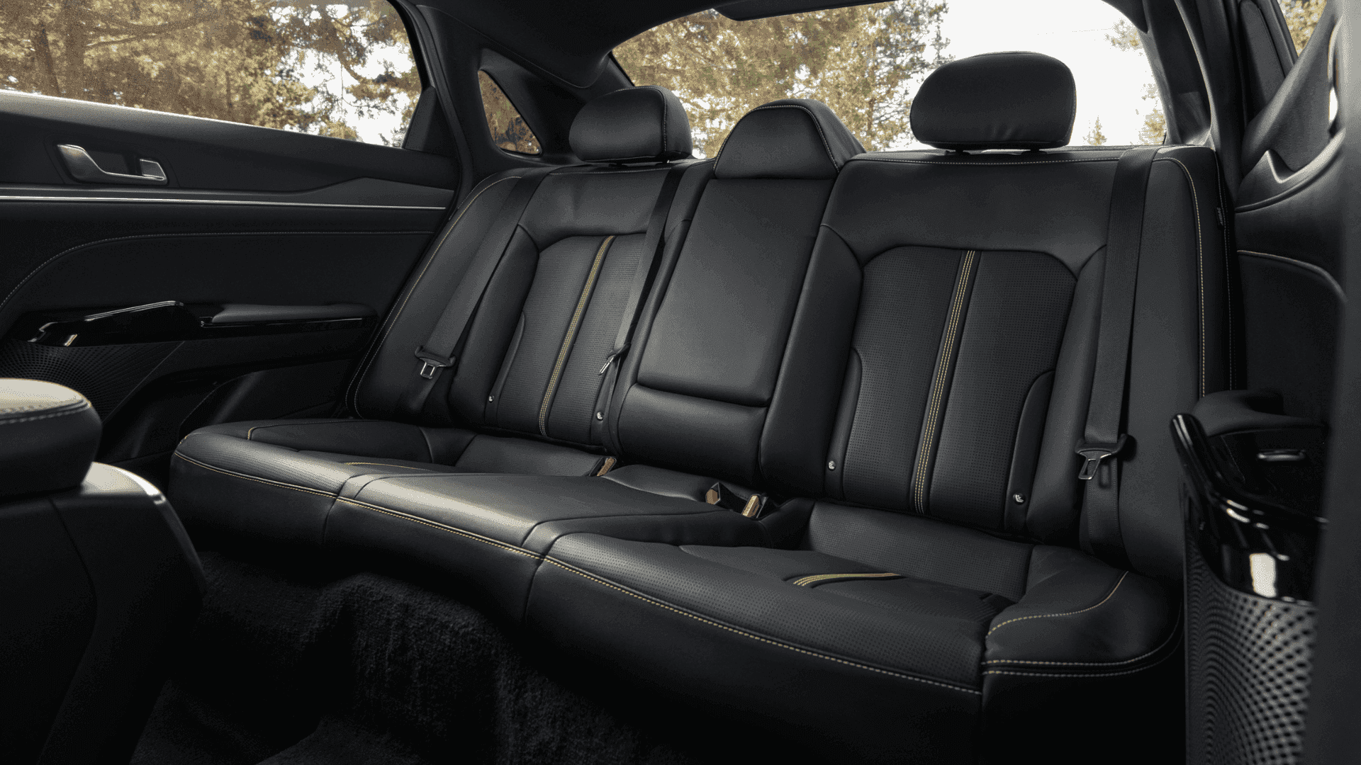 2025 Kia K5 rear seating with black leather upholstery and contrast stitching, offering spacious comfort and a refined cabin experience.