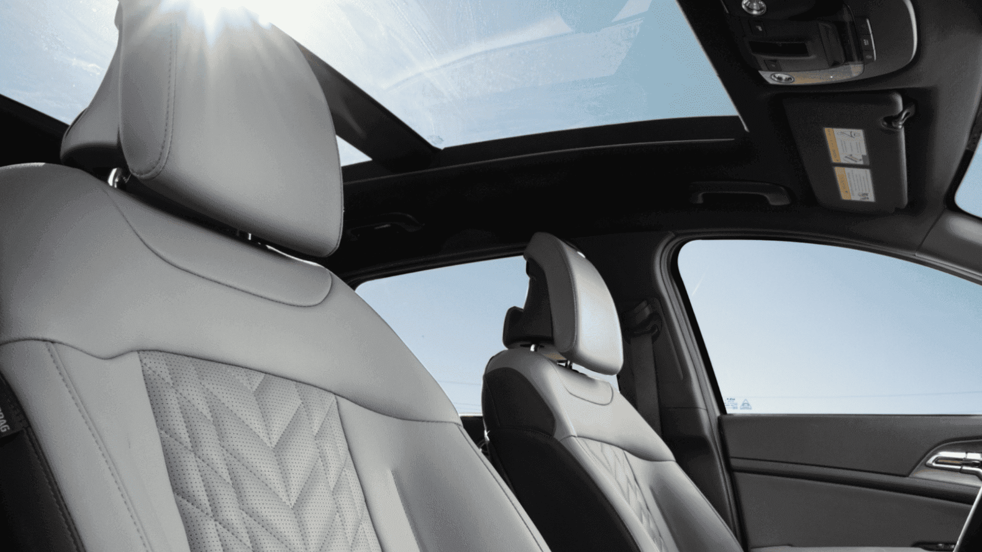 Interior view of the 2025 Kia Sportage highlighting the leather-trimmed front seats and panoramic sunroof for an open-air driving experience.
