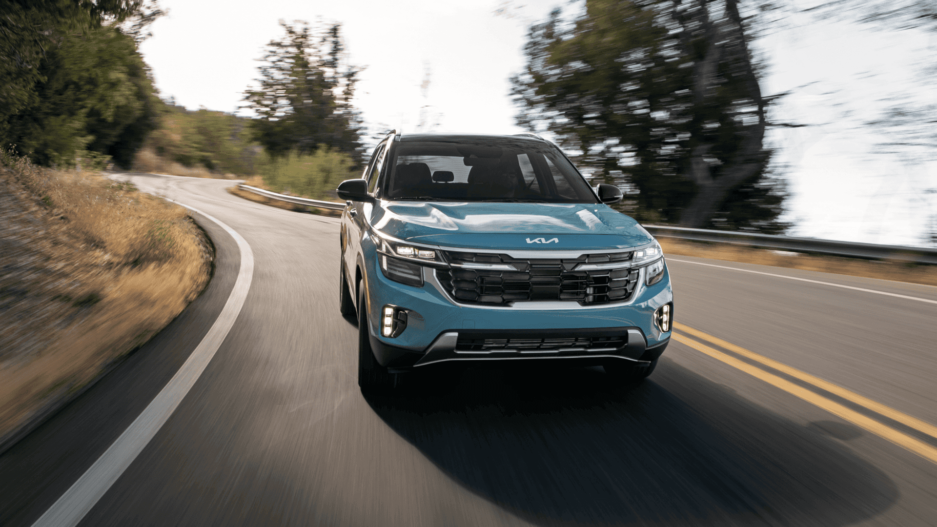 Front view of the 2025 Kia Seltos in motion on a winding road, featuring refreshed styling and dynamic performance.