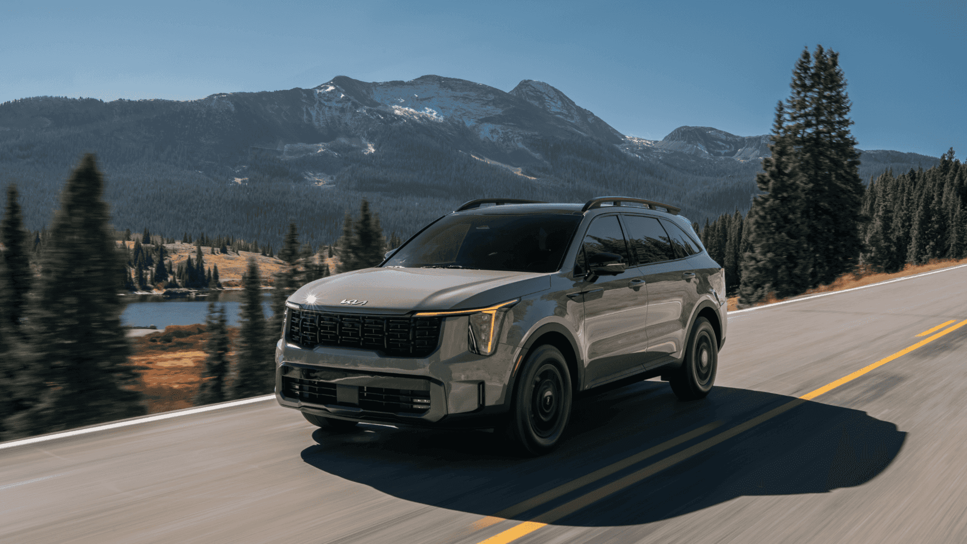 2025 Kia Sorento SUV driving on a mountain highway with scenic views, showcasing its rugged capability and modern design.