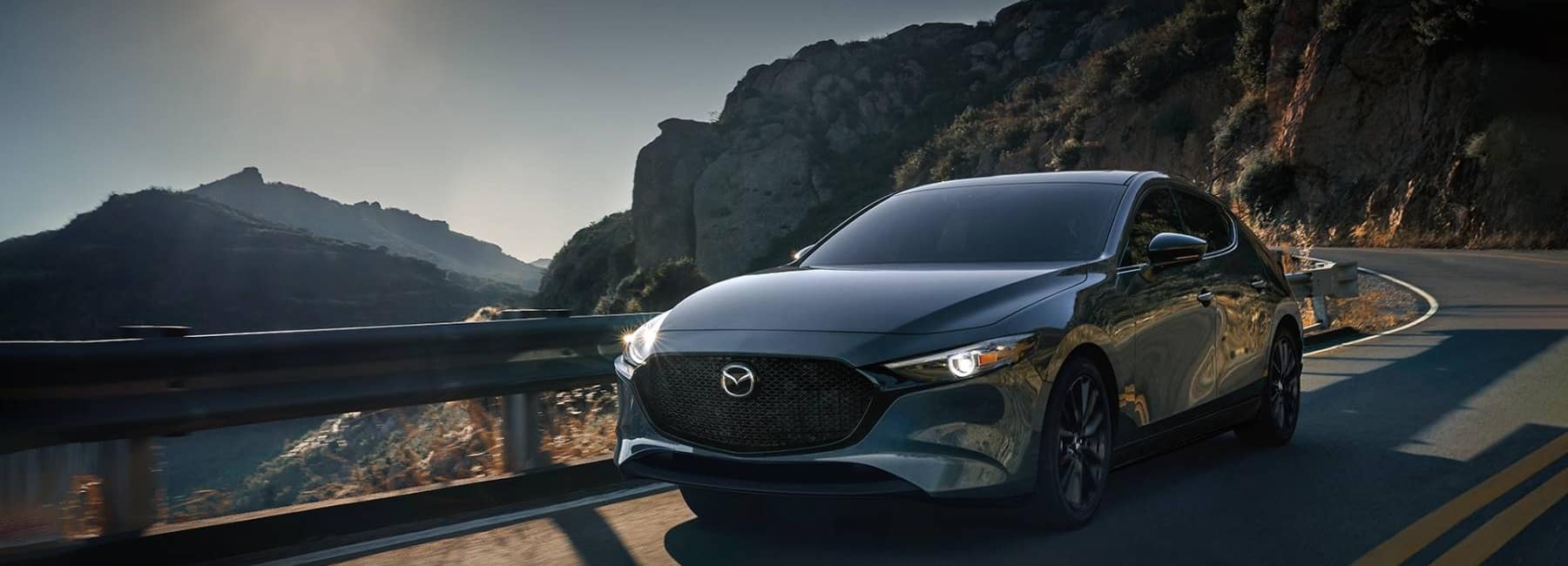 2021-mazda-3-hatchback-compact-car-3qview-driving-mountain-road-grey