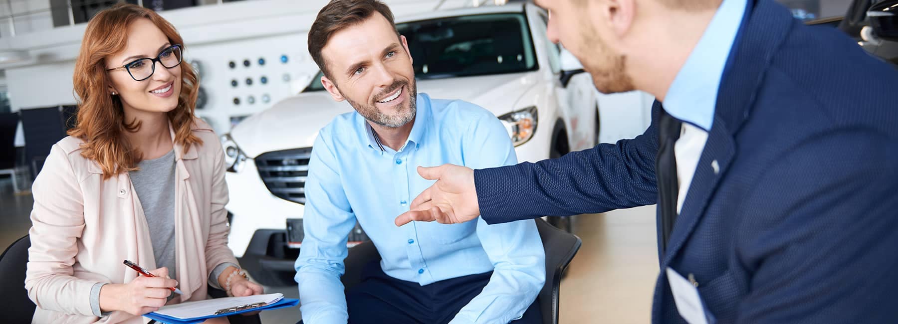 happy couple talks with car salesman
