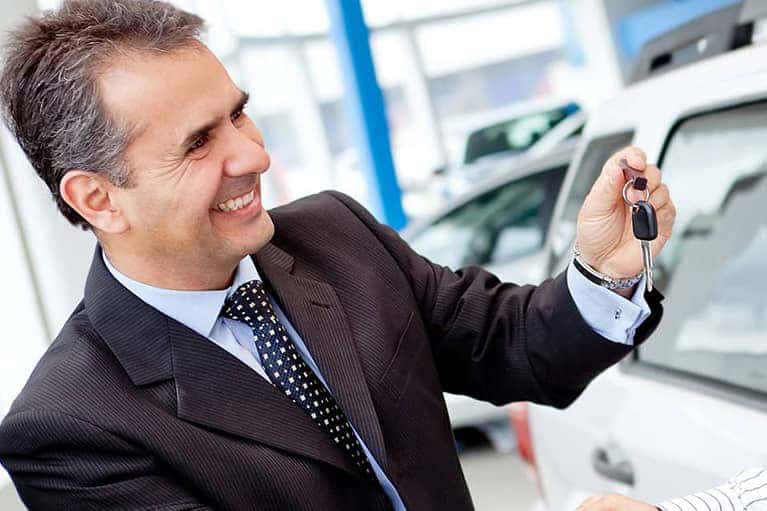 smiling salesman hands over car keys