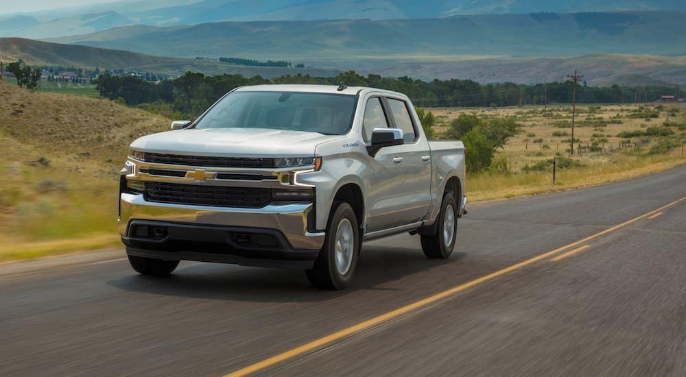 A silver 2021 Chevy Silverado 1500 LT from a Chevy dealer near you is driving on an empty highway.