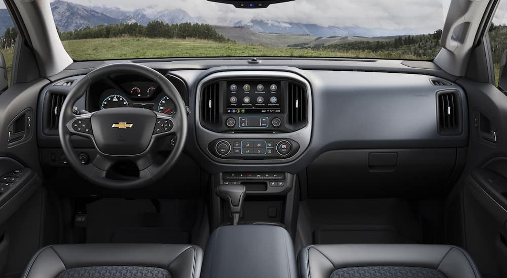 The black interior of a 2021 Chevy Colorado shows the steering wheel and infotainment screen.