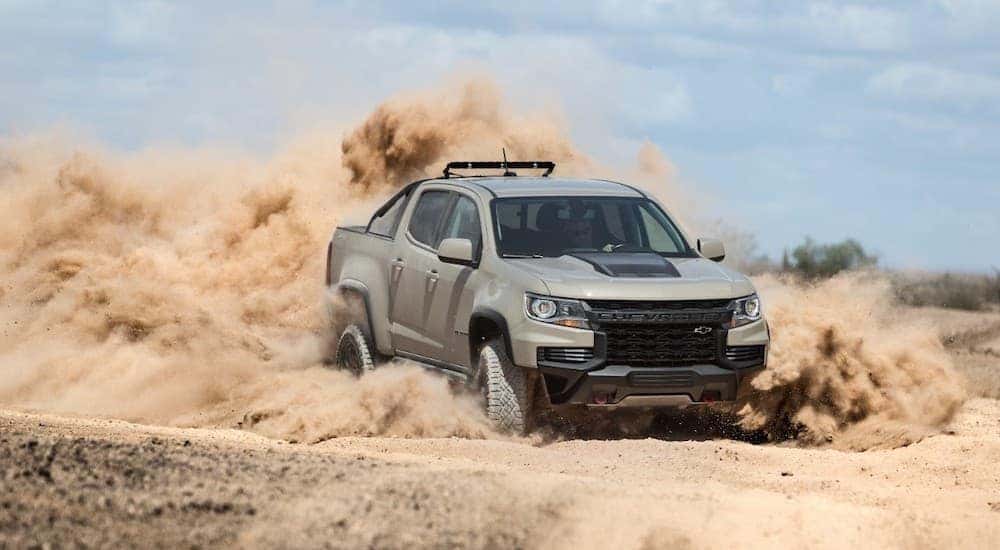 A tan Chevy truck, the 2021 Chevy Colorado ZR2, is shown off-roading in the desert.