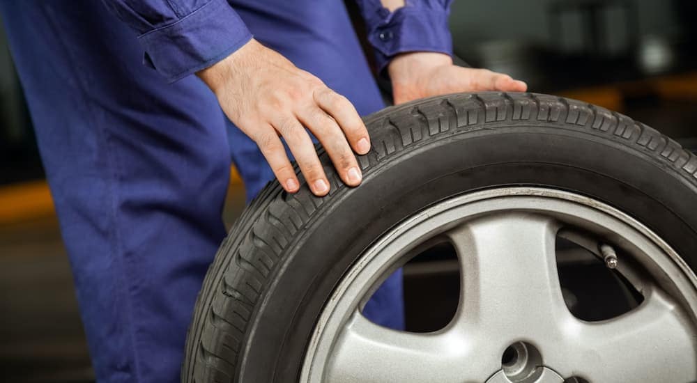 A mechanic is shown rolling a tire at a service center.