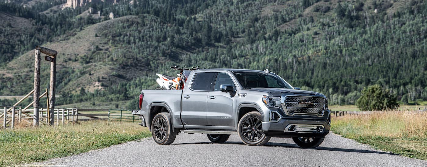 A grey 2021 GMC Sierra 1500 Denali CarbonPro is shown with a dirt bike in the bed.