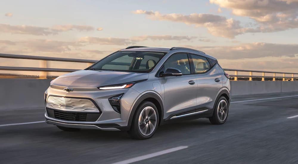 A new Chevy SUV, a silver 2022 Chevy Bolt EUV, is driving on a highway.