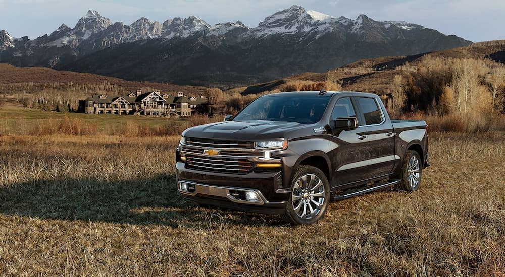 A black 2022 Chevy Silverado 1500 High Country is shown parked in a dry grassy field near a Booneville GM dealership.