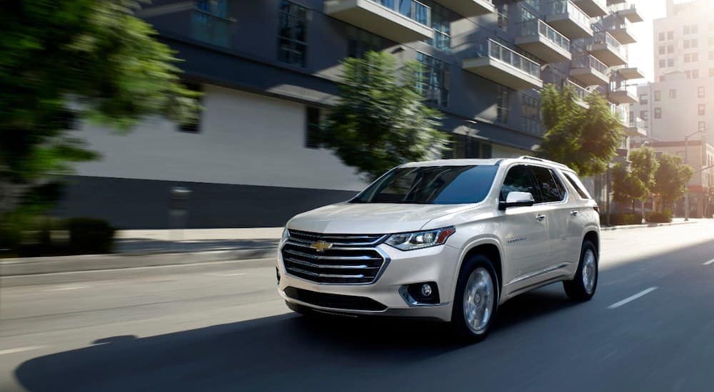 A white 2020 Chevy Traverse High Country is shown driving on a city street.