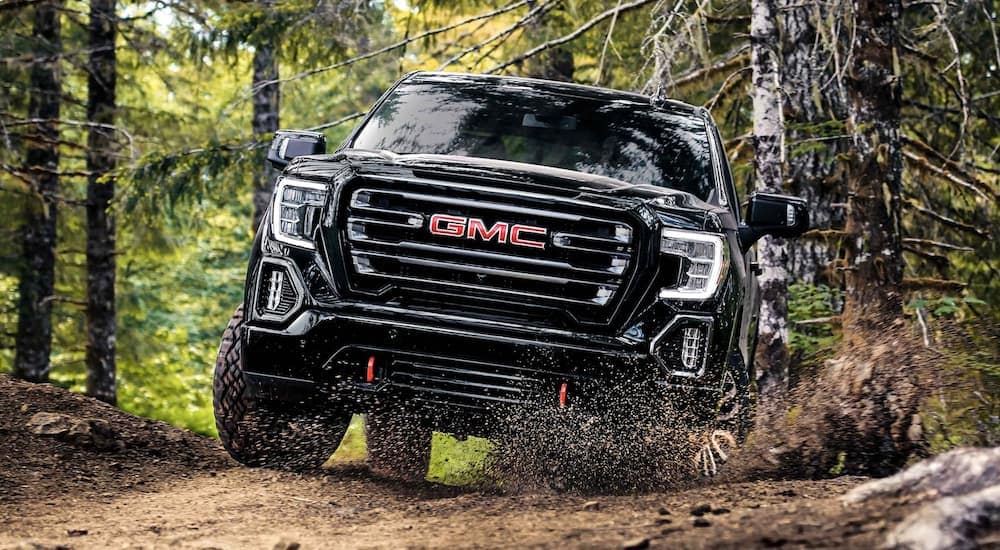 A black 2022 GMC Sierra 1500 AT4 is shown off-roading on a path after leaving a Booneville GM dealership.