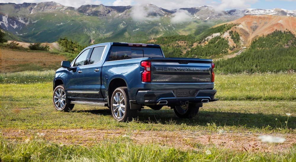 A dark blue 2022 Chevy Silverado 1500 High Country is shown from the rear parked in a field.