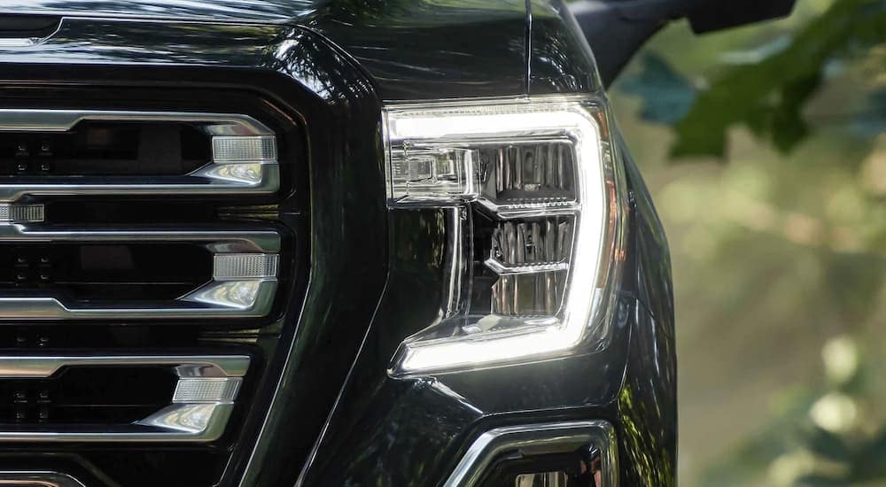 A close up shows the headlight on a black 2022 GMC Sierra 1500 AT4.