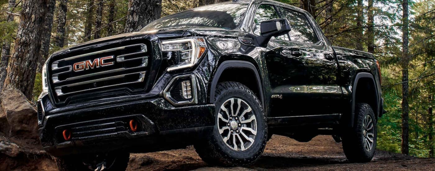 A black 2021 GMC Sierra 1500 AT4 is parked on a trail in the woods.