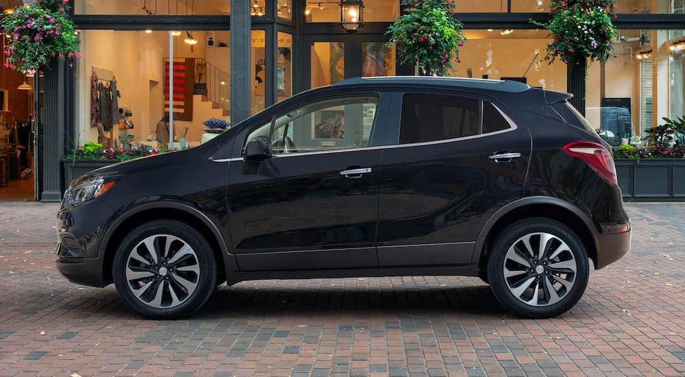 A black 2022 Buick Encore is shown from the side parked near a store front.