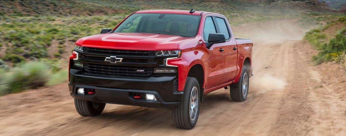 A red 2020 Chevy Silverado 1500 TrailBoss Z71 is shown driving on a dirt road after visiting a Chevy dealer near you.