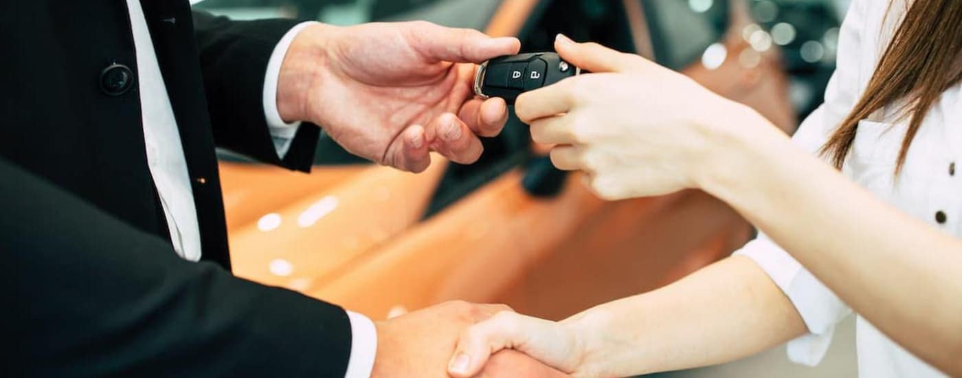 A salesperson is shaking hands with a customer at a GM lease turn in.