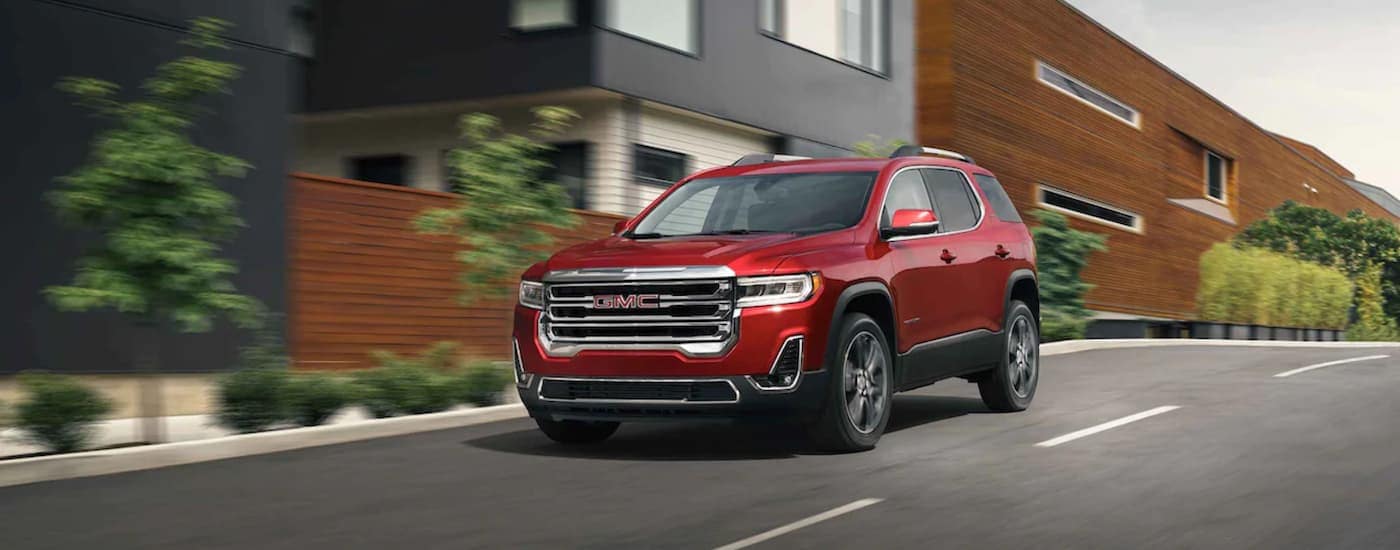 A red 2021 GMC Acadia is shown from the front driving on an open road.