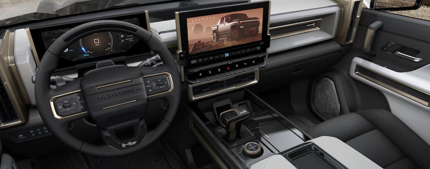 The black and white interior of a 2022 GMC Hummer EV shows the steering wheel and infotainment screen.