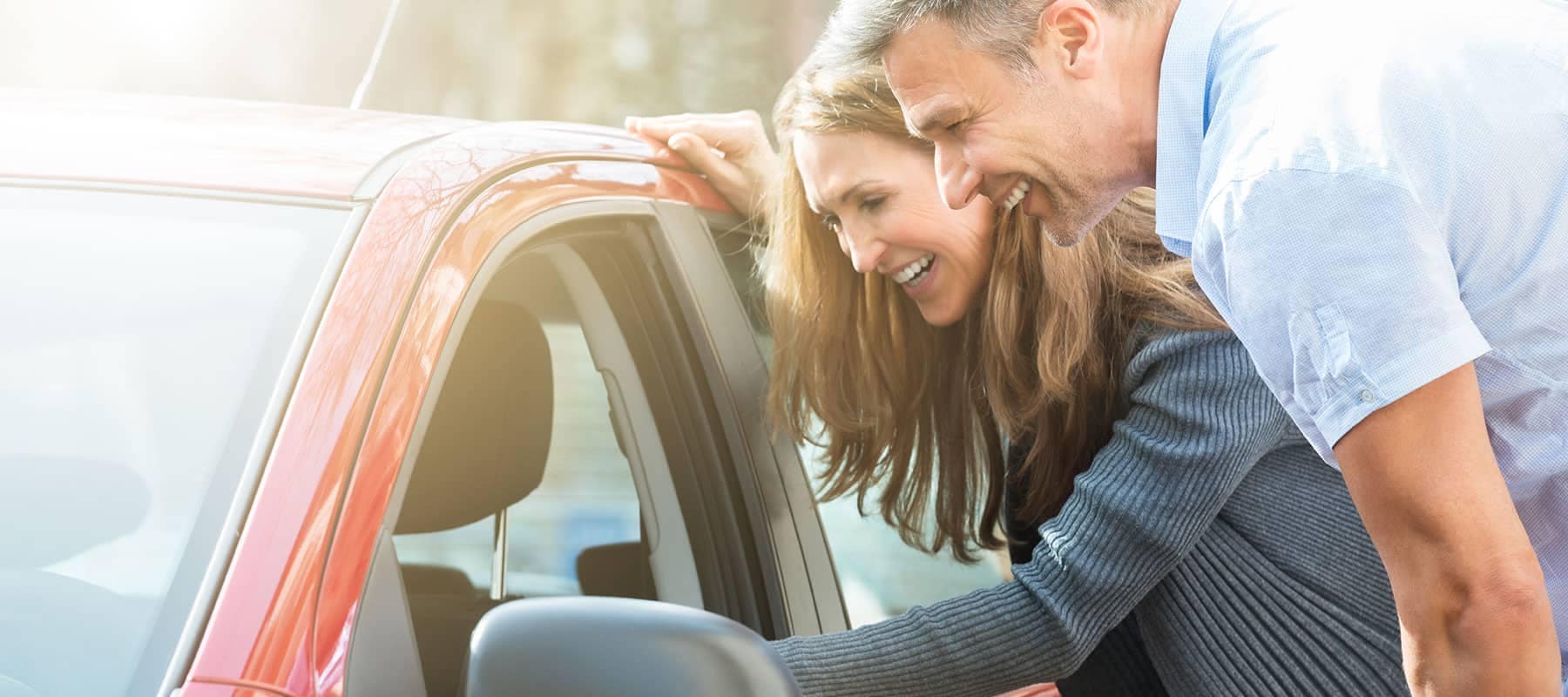 smiling couple examining a car