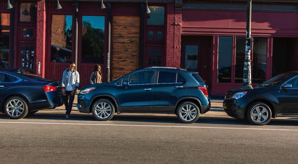 A couple is walking towards a blue 2021 Chevy Trax that is shown from the side and parked on a Lexington street.