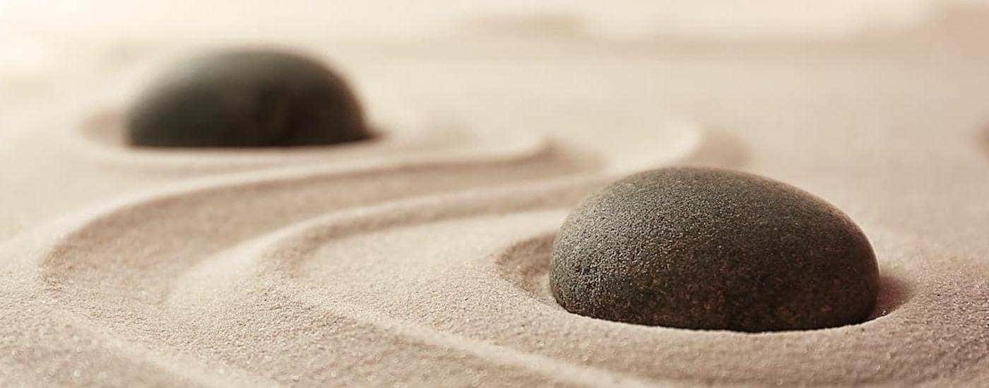 Two black stones are shown in a zen garden.