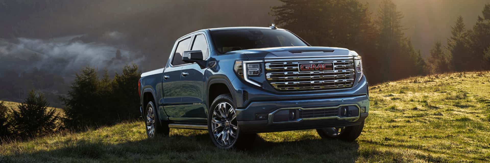 GMC-truck-parked-on-grassy-hills-with-sun-shining-on-the-hood