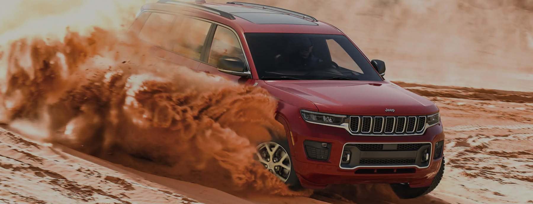 red jeep driving through desert sand