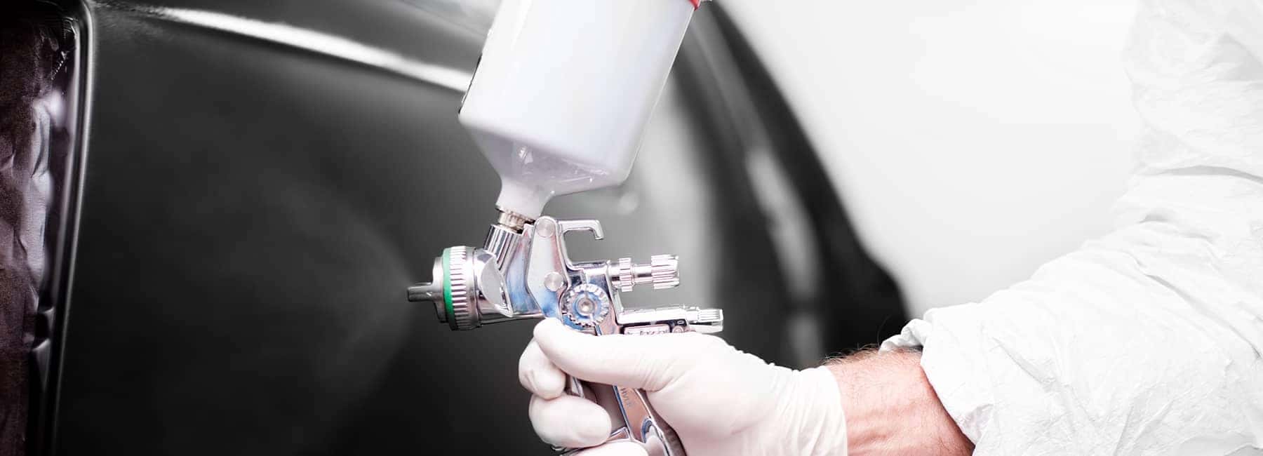 technician sprays car with professional sprayer