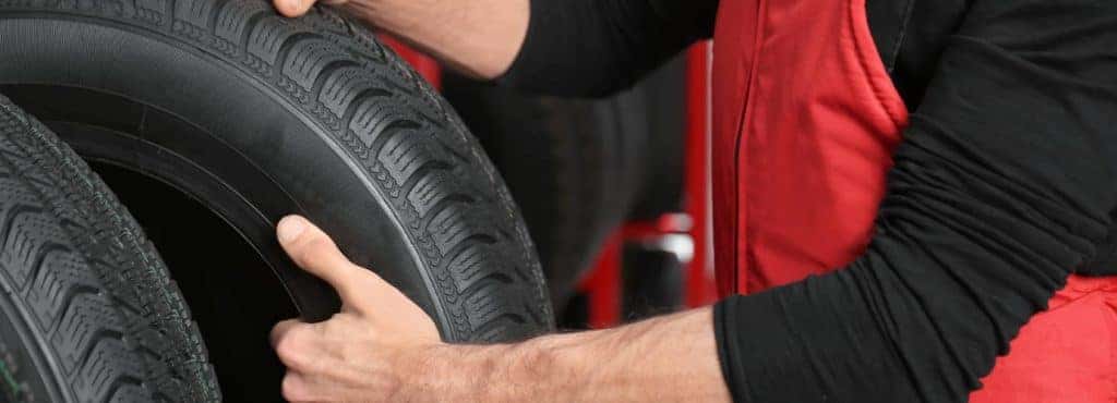 Mechanic hoisting new car tires
