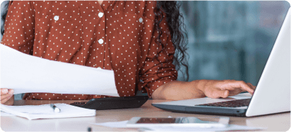Lady typing on laptop while holding paper