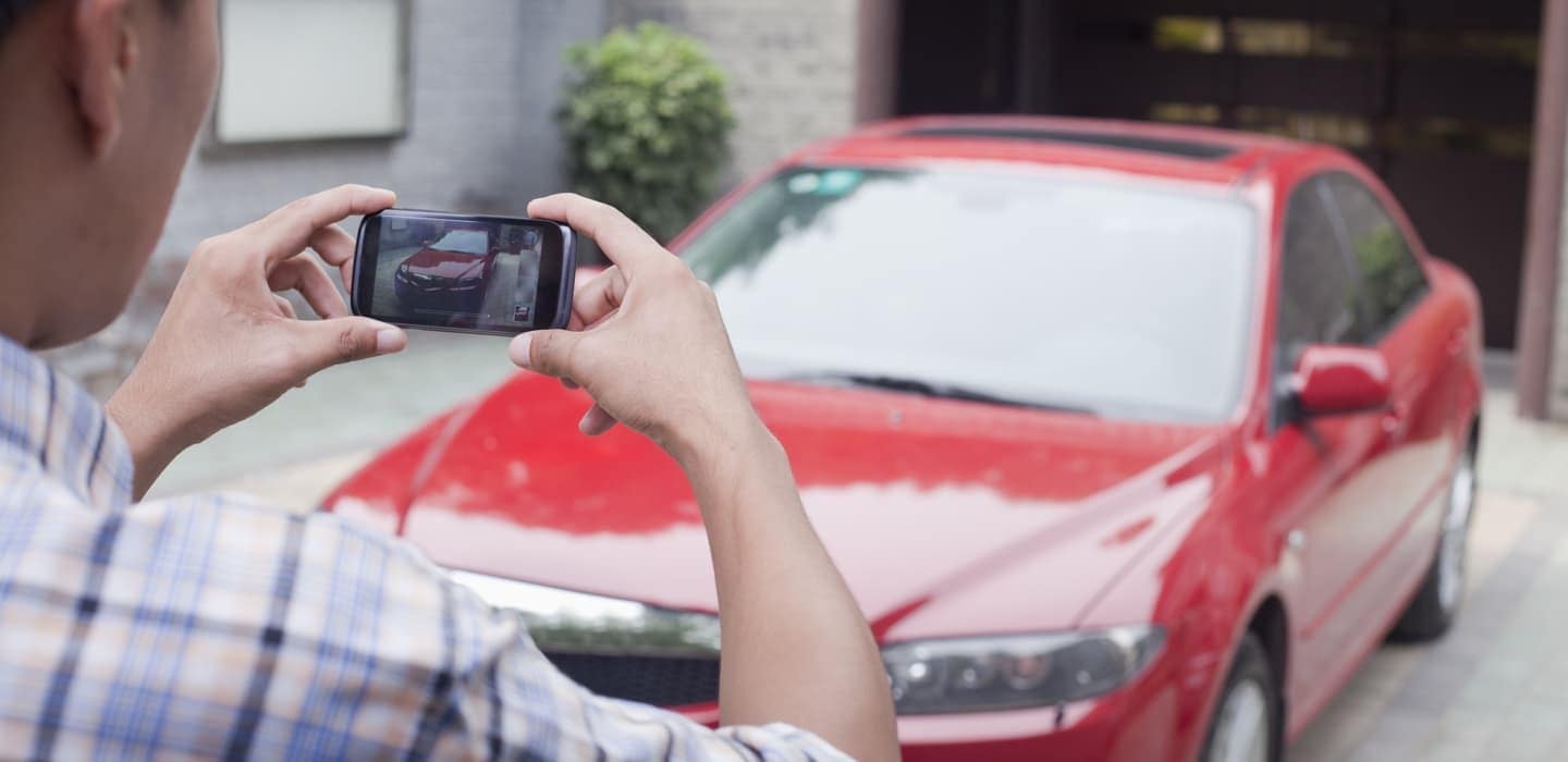 Man taking photo of car on cell phone