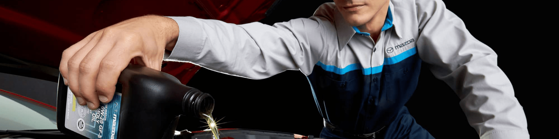 Mazda technician pours oil in car engine