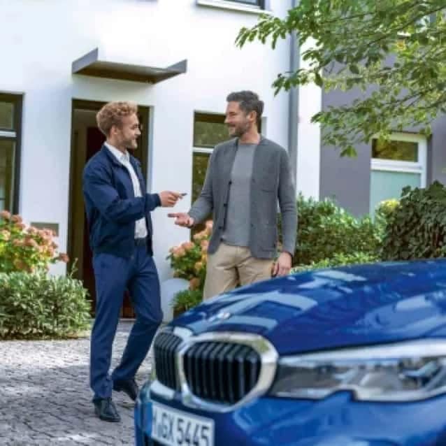 Salesman handing off keys to customer with blue BMW