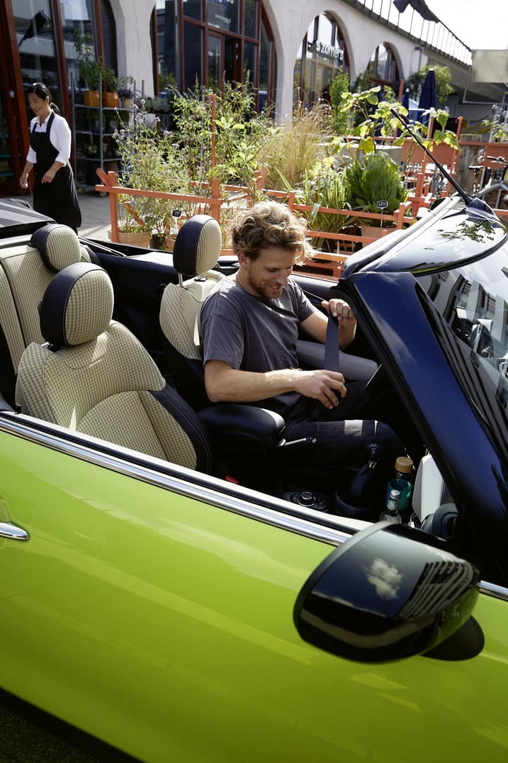 Young man sitting in a bright green MINI