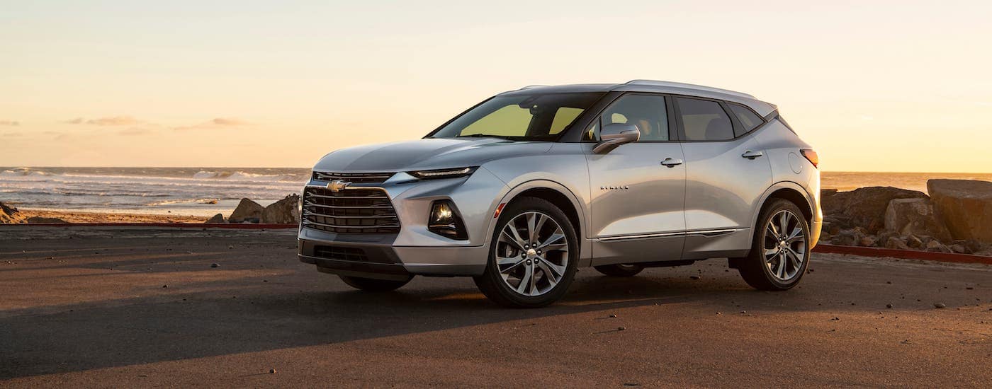 A silver 2020 Chevy Blazer is parked in front of a beach at sunset.