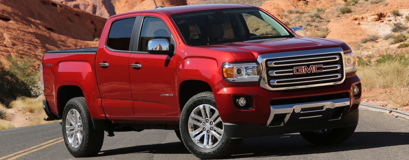A red 2020 GMC Canyon, which is a popular model at your local GMC dealer, is parked across a desert highway.