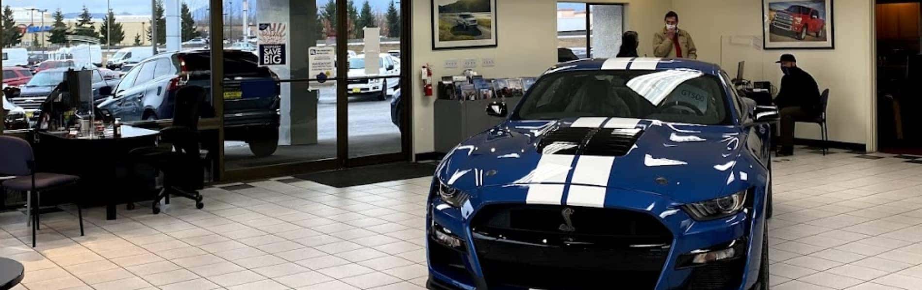 blue car with white strips on showroom floor