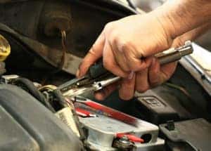 Battery picture of technician hands unscrewing battery post