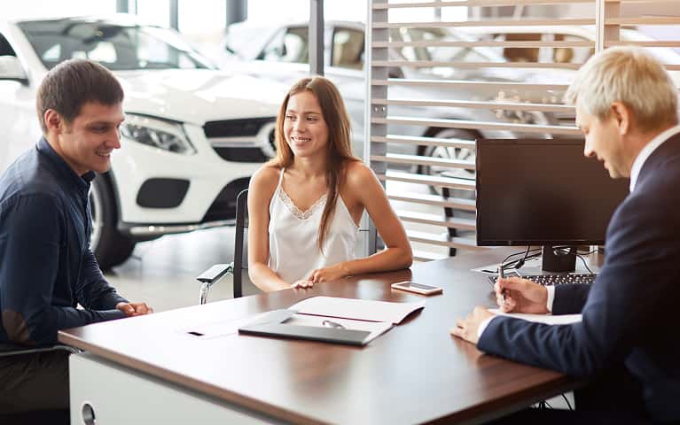 Customers sitting at a desk with the salesperson.