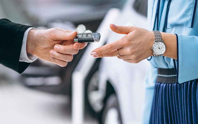 Person handing over a key fob to another person's hand