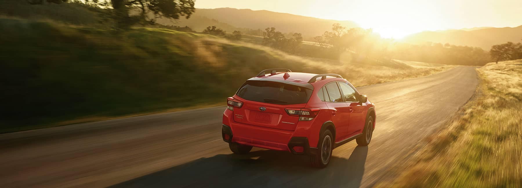 2022 Subaru Crosstrek driving on a country road into the sunset
