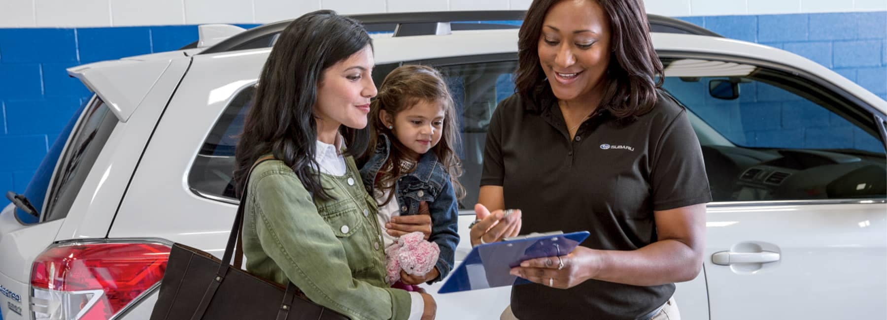 Subaru Advisor discussing options with a female customer and her child