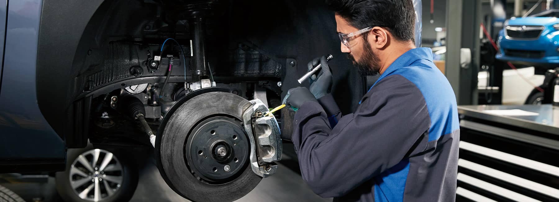 Subaru Service Technician performing a brake pad inspection