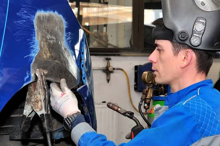 technician repairs body on blue car