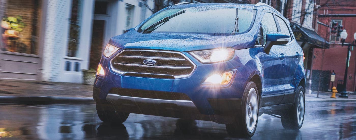 A blue 2021 Ford EcoSport is driving in the rain on a city street after leaving a local Ford dealer."A blue 2021 Ford EcoSport is driving in the rain on a city street after leaving a local Ford dealer.
