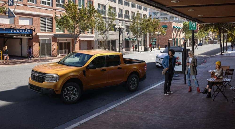 A yellow 2022 Ford Maverick is parked on a city street after leaving a Colorado Ford Maverick dealer.